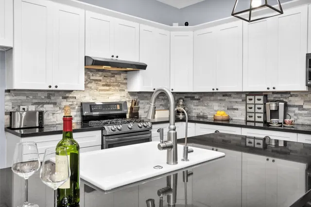 a kitchen with stainless steel appliances granite countertop a sink a stove and white cabinets