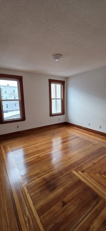 25 Bennett Street, Unit 2 Beverly, MA 01915 - Photo 13 of 17 an empty room with wooden floor and windows