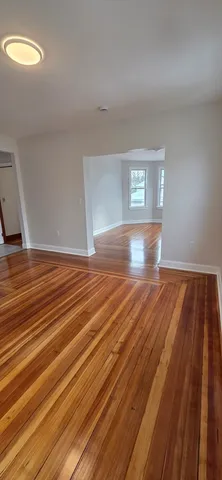 a view of empty room with window and wooden floor