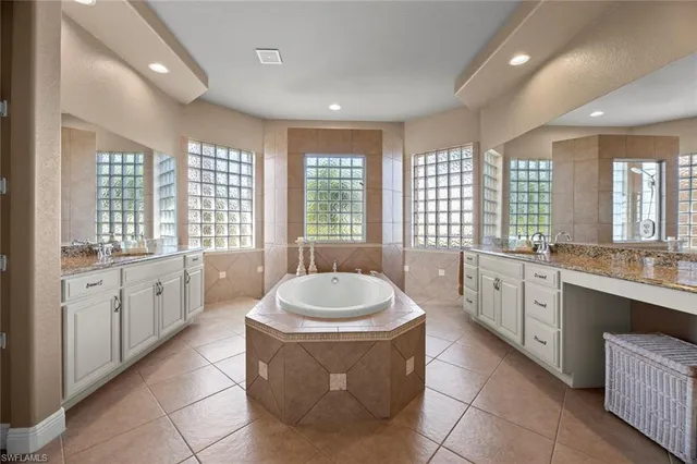 a large spacious bathroom with a double vanity sink a large mirror and a bathtub