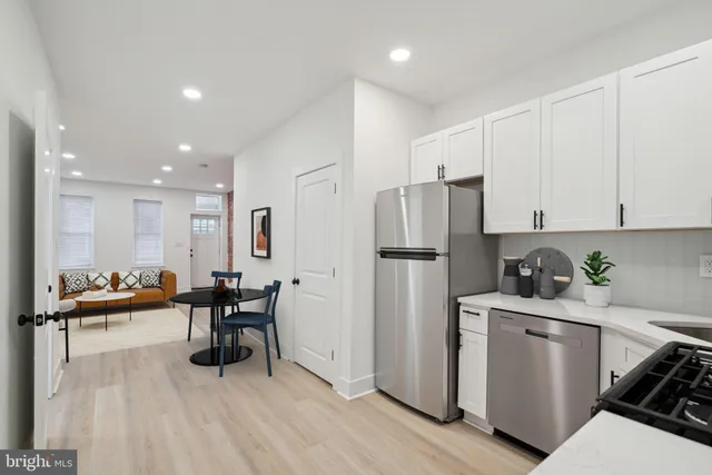 a kitchen with stainless steel appliances a refrigerator a stove a sink dishwasher and white cabinets with wooden floor