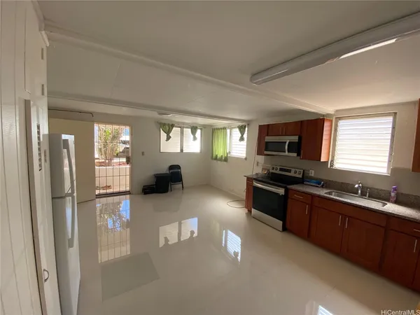 a large kitchen with stainless steel appliances granite countertop a refrigerator a sink dishwasher a stove and white countertops with wooden floor