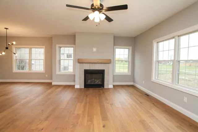 a view of an empty room with window and wooden floor