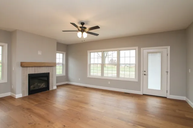a view of empty room with a fireplace wooden floor and windows