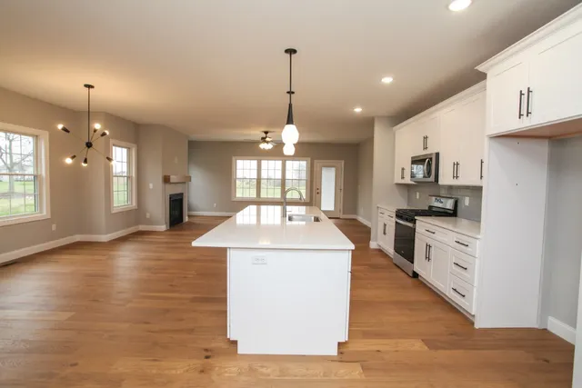 a large kitchen with kitchen island a stove a sink a center island and wooden floor