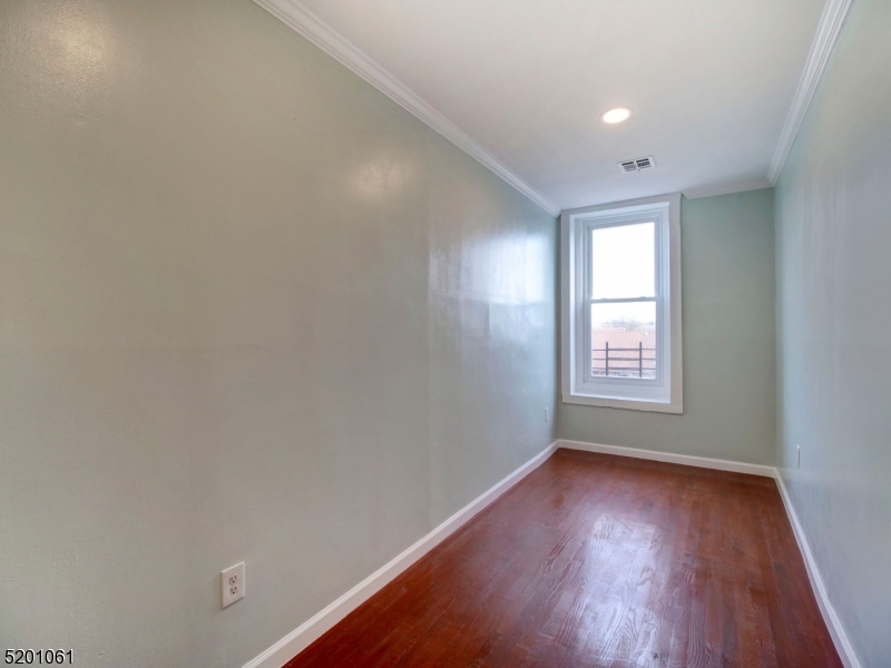 310 Broadway Newark, NJ 07104 - Photo 11 of 11 an empty room with wooden floor and windows