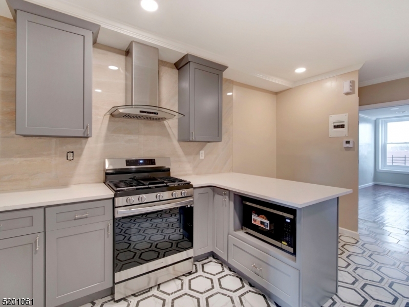 310 Broadway Newark, NJ 07104 - Photo 6 of 11 a kitchen with granite countertop a stove a sink and a microwave