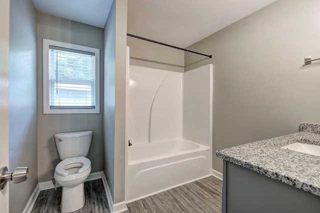 a bathroom with a granite countertop toilet a sink and bathtub