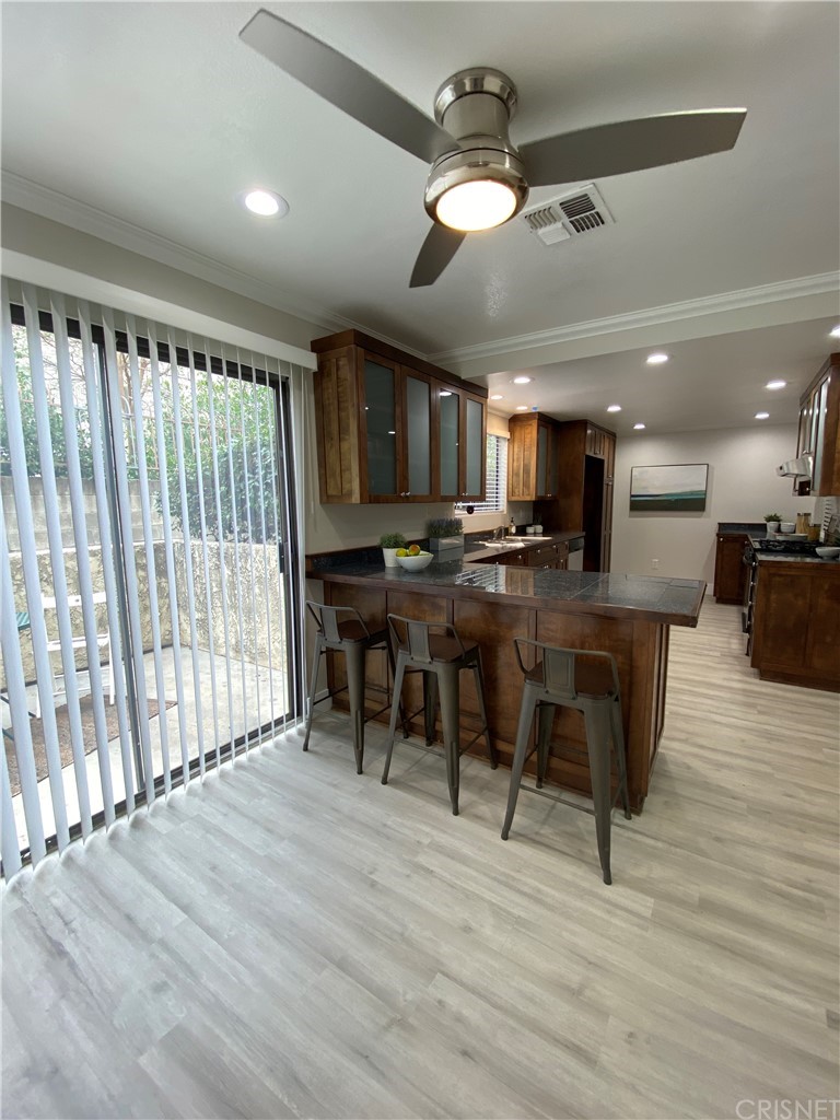 9960 Owensmouth Avenue, Unit 25 Chatsworth, CA 91311 - Photo 8 of 17 a open kitchen with stainless steel appliances granite countertop a stove top oven a refrigerator a dining table and chairs with wooden floor