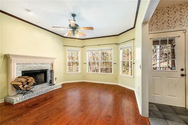 a view of an empty room with wooden floor fireplace and a window