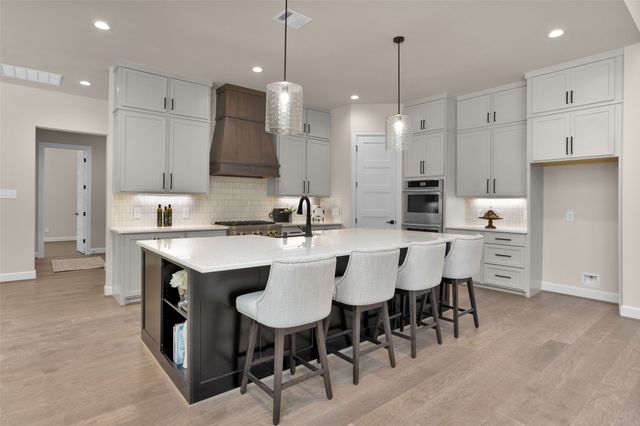 a kitchen with stainless steel appliances kitchen island granite countertop a table chairs and a refrigerator