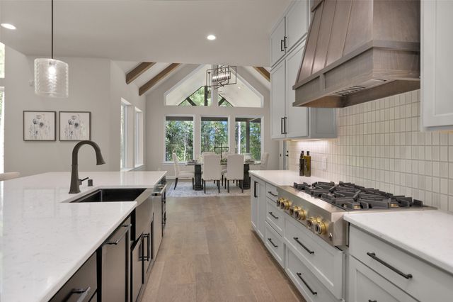 a kitchen with kitchen island granite countertop a stove a sink a refrigerator and white cabinets with wooden floor