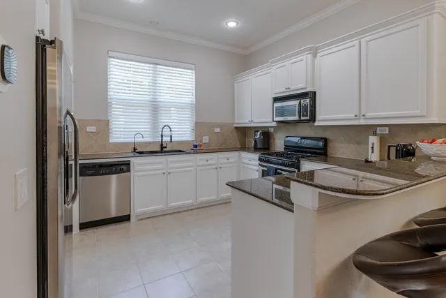 a kitchen with stainless steel appliances granite countertop a sink stove a refrigerator and white cabinets