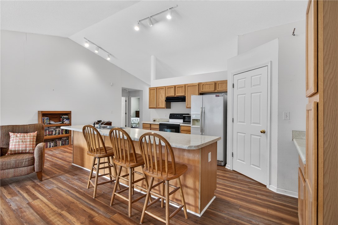 207 Hunters Lane Anderson, SC 29625 - Photo 13 of 46 The kitchen boasts a central island and a vaulted ceiling, seamlessly flowing into the living area. The door leads to the large laundry room which then leads out to the garage.