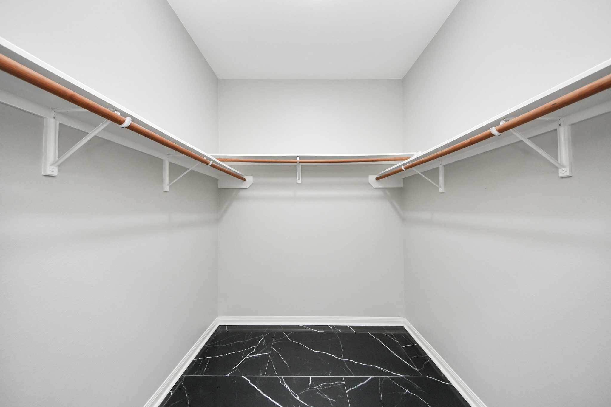 6931 Primrose Road Baytown, TX 77521 - Photo 26 of 50 Spacious walk-in closet with dual hanging racks and sleek black tile flooring.