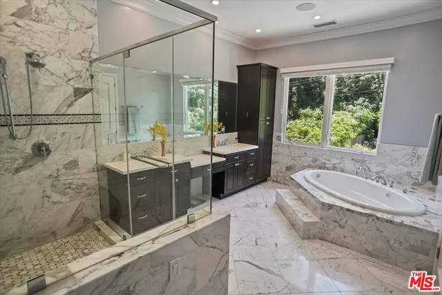 a bathroom with a double vanity sink a large mirror and a bathtub