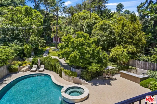 a view of a backyard with table and chairs potted plants and large tree