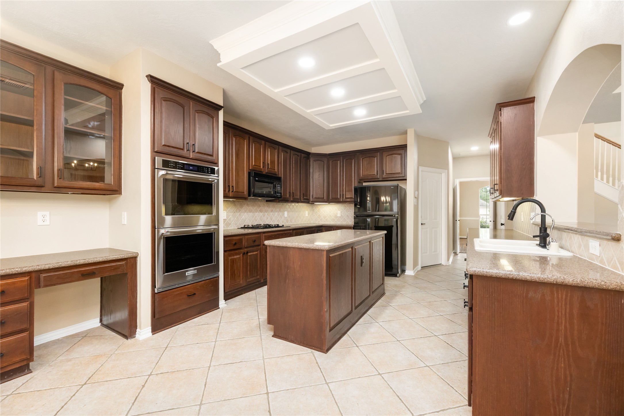 6518 Briarstone Lane Spring, TX 77379 - Photo 14 of 46 The spacious kitchen has a functional layout, featuring a central island, ample counter space and a built-in desk offering a blend of functionality and sophistication.