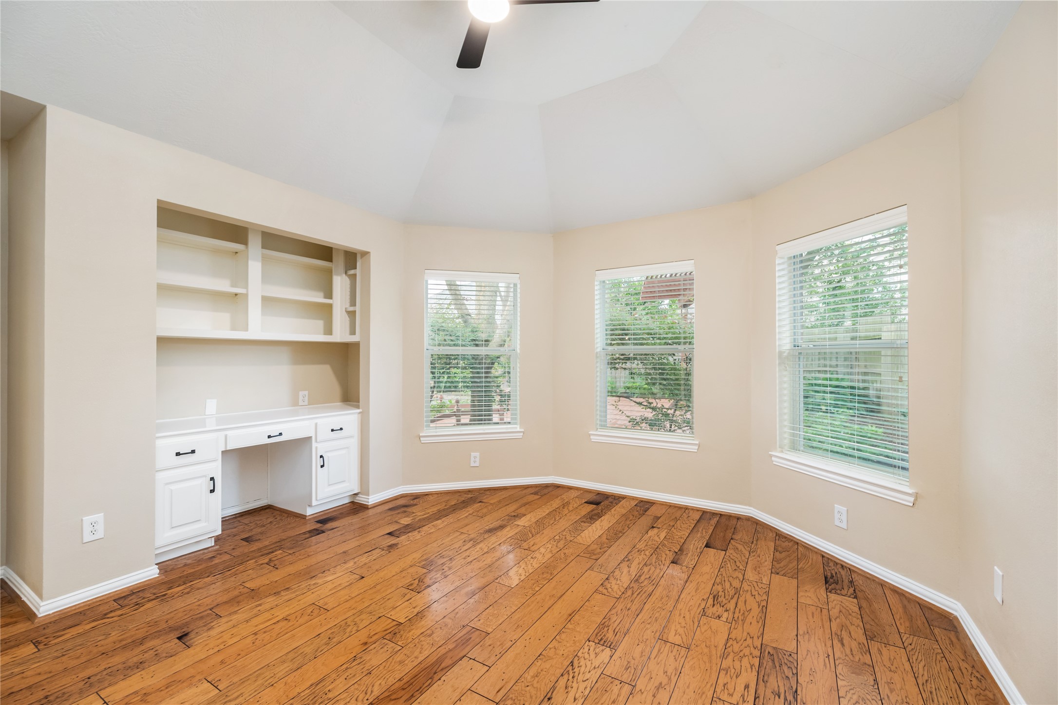 6518 Briarstone Lane Spring, TX 77379 - Photo 17 of 46 Warm hardwood floors, a built-in desk with shelving, and three expansive windows combine to create a bright and functional space—perfect for work, study, or creativity.