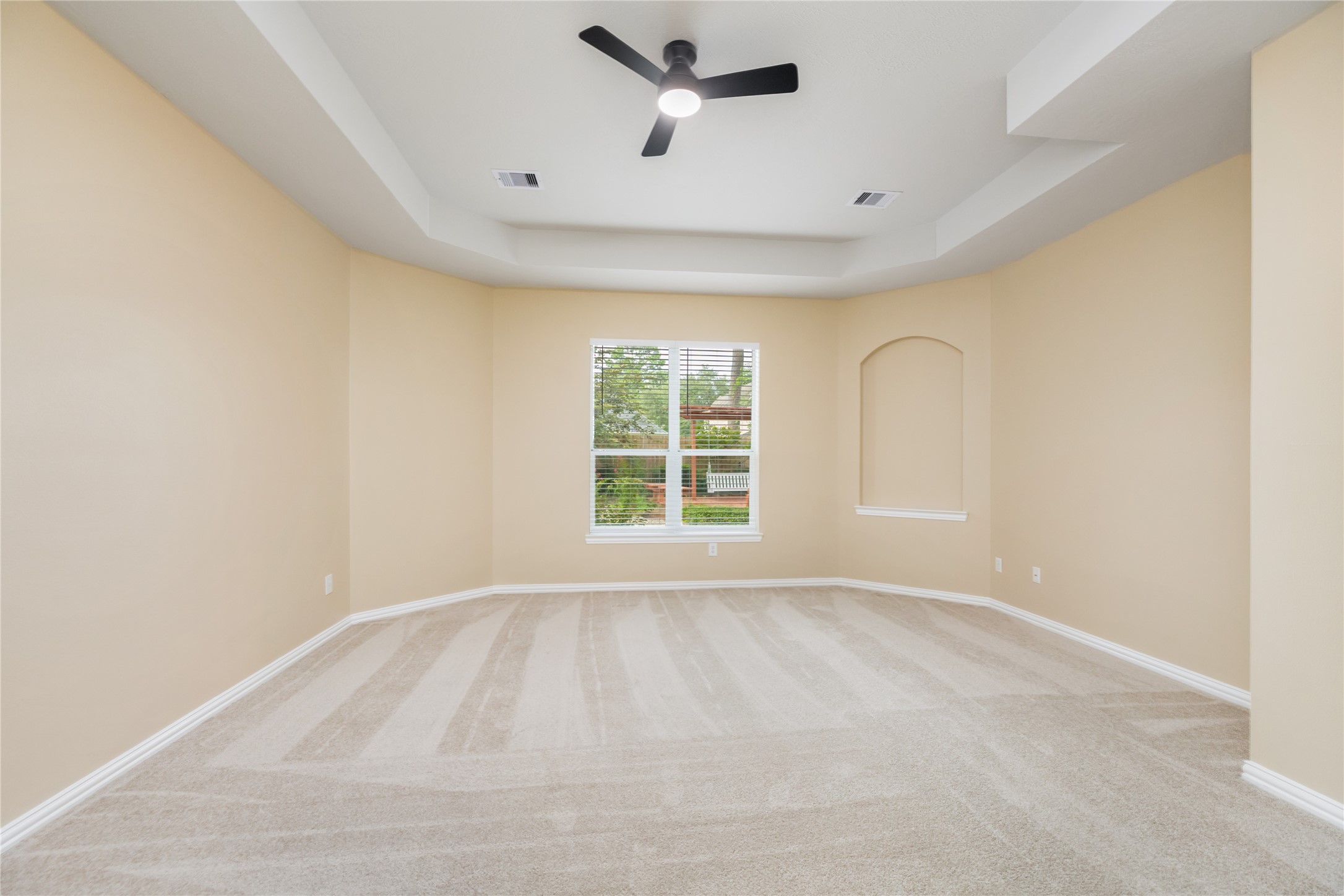 6518 Briarstone Lane Spring, TX 77379 - Photo 19 of 46 Featuring neutral walls and carpet, this spacious primary bedroom has high ceilings with a fan, and a window that overlooks the serene backyard.