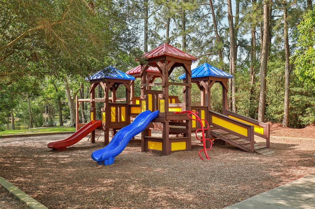 6518 Briarstone Lane Spring, TX 77379 - Photo 44 of 46 A colorful playground nestled among tall trees provides a safe and shaded outdoor space for children to play and explore.