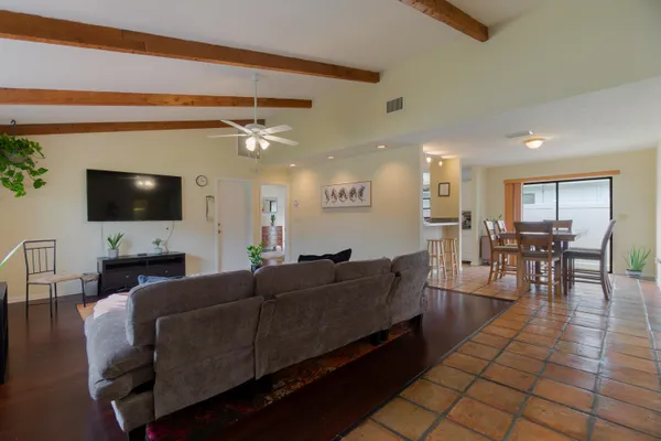 a living room with furniture a flat screen tv and kitchen view