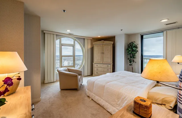 a bedroom with a bed and large windows