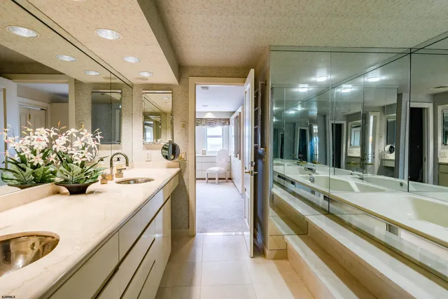 a bathroom with a sink and mirror with bathtub