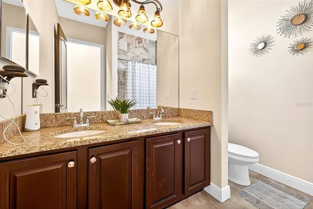 a bathroom with a granite countertop sink and a toilet