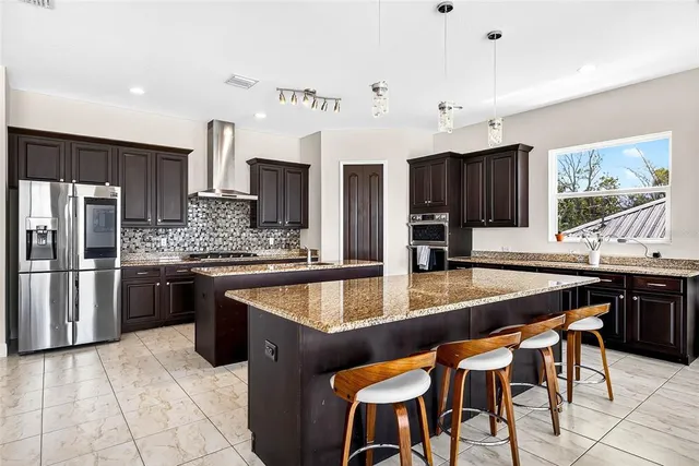 a kitchen with stainless steel appliances granite countertop a table chairs sink refrigerator and cabinets