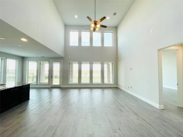 an empty room with wooden floor fan and windows