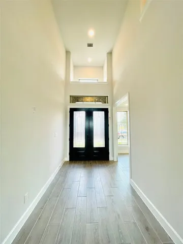 a view of an empty room with a window and wooden floor