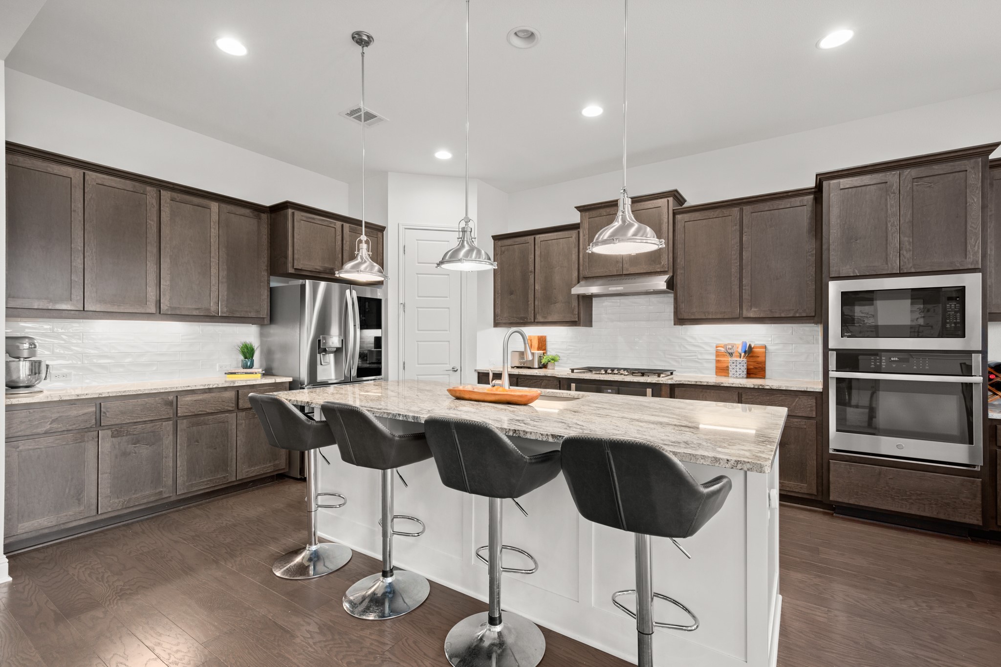 330 Cistern Way Austin, TX 78737 - Photo 23 of 40 a kitchen with kitchen island granite countertop wooden cabinets and a stove