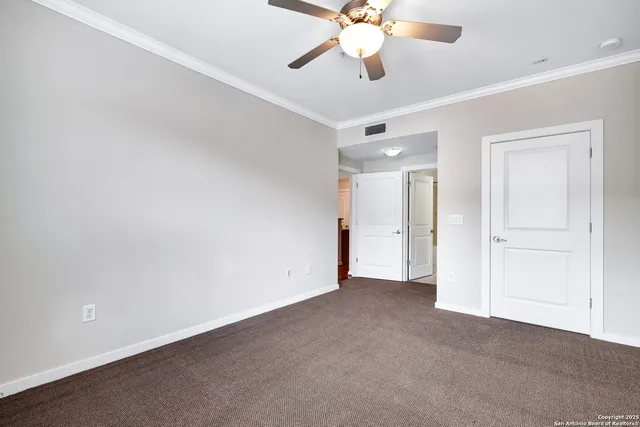 an empty room with a chandelier fan and closet area