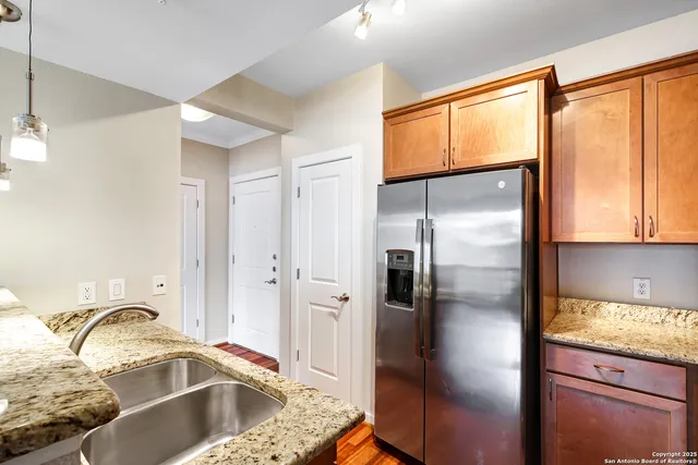 a kitchen with granite countertop a refrigerator and a sink