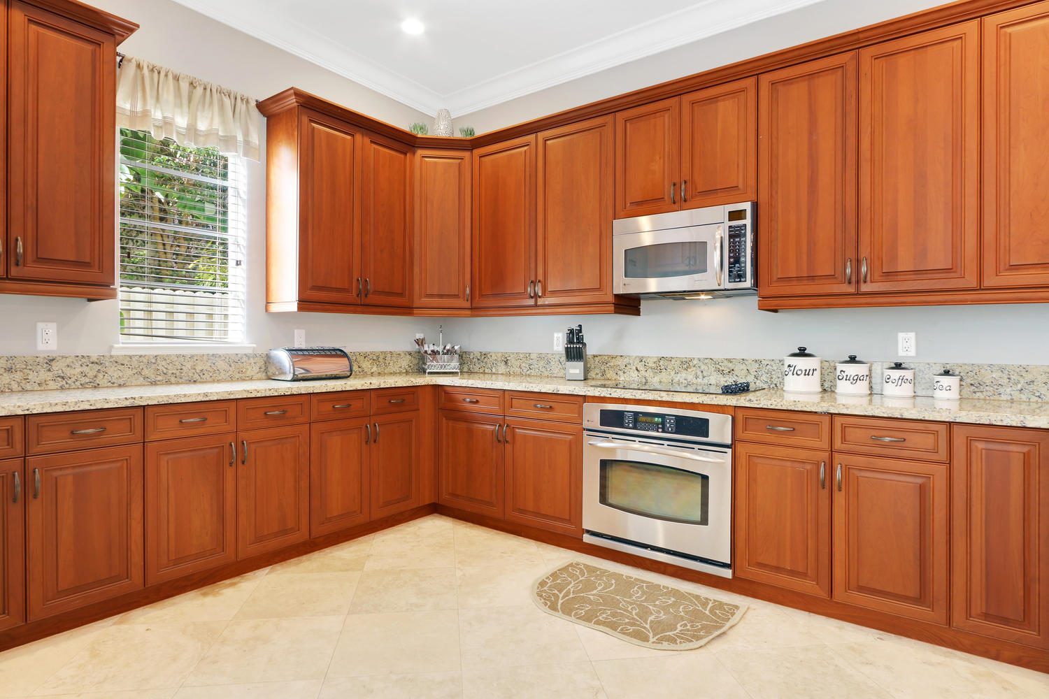 98 Via Poinciana Lane Boca Raton, FL 33487 - Photo 13 of 38 a kitchen with granite countertop wooden cabinets a sink a stove a window and stainless steel appliances