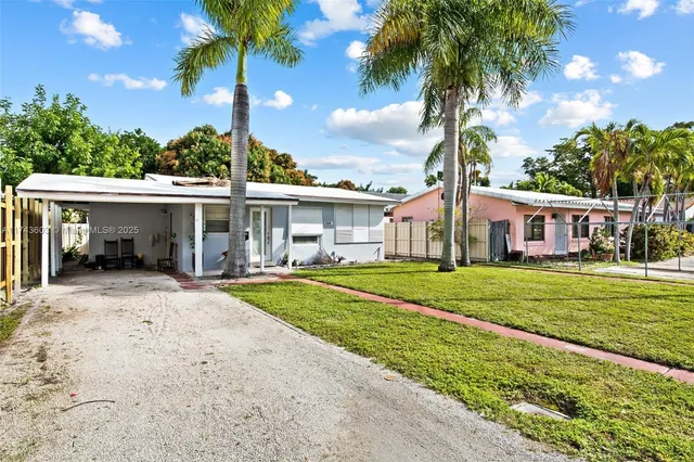 front view of a house with a yard and palm trees
