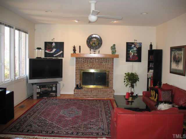 1809 Sarazen Place Raleigh, NC 27615 - Photo 4 of 9 a living room with furniture a flat screen tv and a fireplace