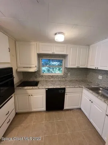 a kitchen with granite countertop a stove top oven sink and cabinets