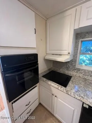 a kitchen with white cabinets and black appliances
