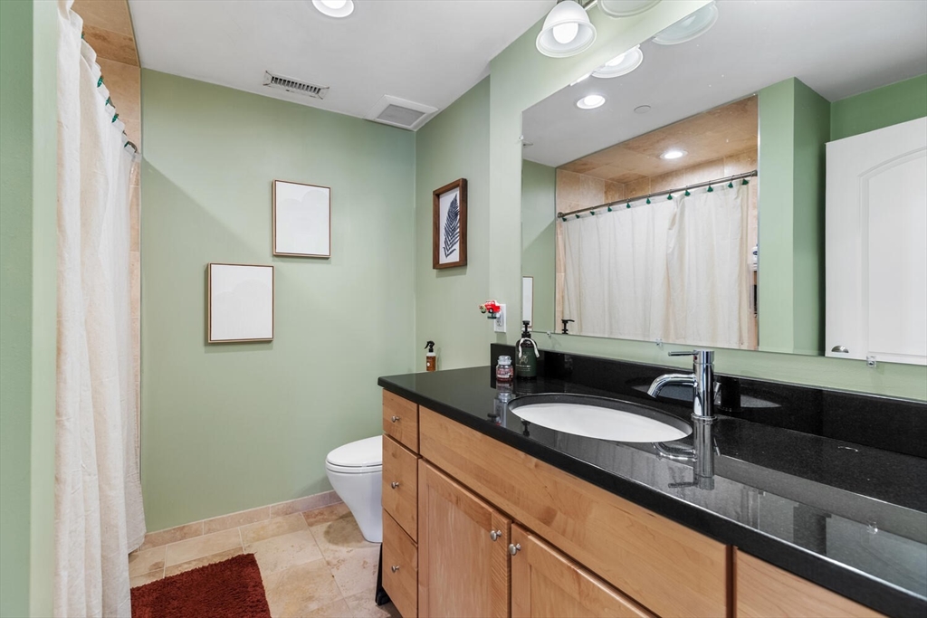 30 High Street, Unit 31 Medford, MA 02155 - Photo 16 of 27 a bathroom with a granite countertop sink a large mirror and a toilet