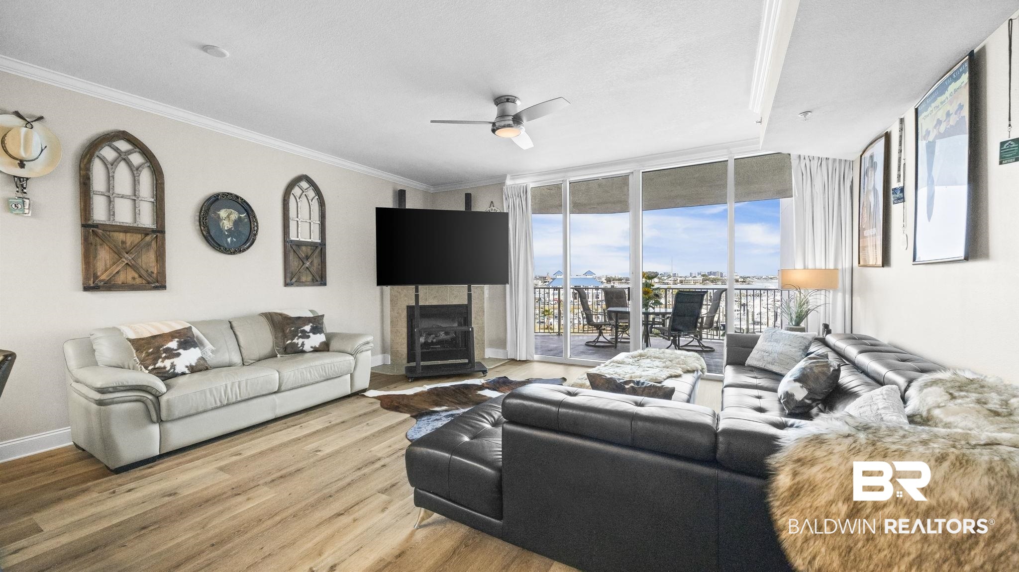 27800 Canal Road, Unit 313 Orange Beach, AL 36561 - Photo 5 of 23 Living room with expansive windows, wood finished floors, a ceiling fan, a tiled fireplace, and crown molding