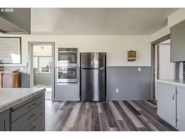 a kitchen with stainless steel appliances a refrigerator and wooden floor