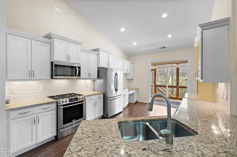 a kitchen with stainless steel appliances granite countertop a sink stove and refrigerator