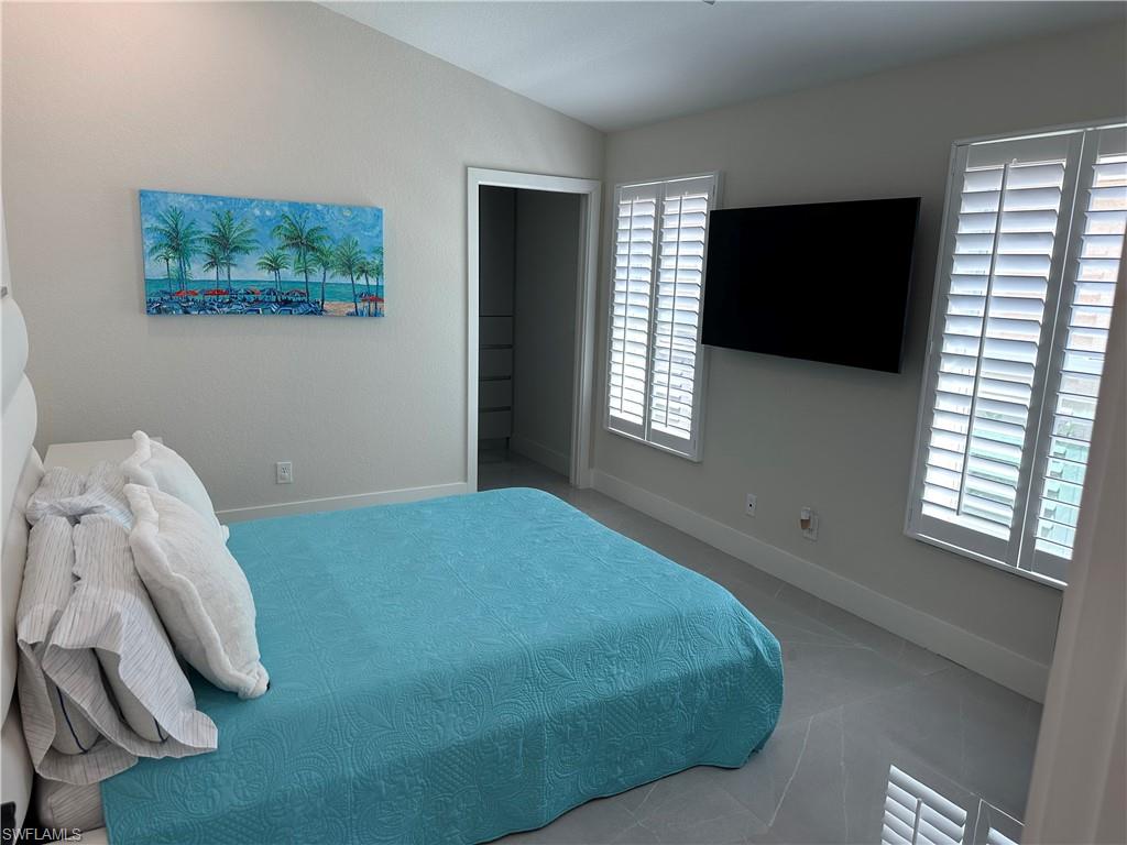 1595 Whispering Oaks Circle Naples, FL 34110 - Photo 11 of 15 a bedroom with a bed and a flat tv screen on the dresser