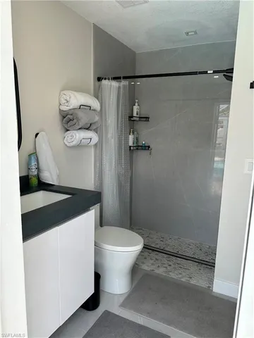 a bathroom with a granite countertop sink a toilet and shower