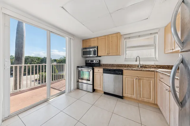 a kitchen with granite countertop a sink window and stainless steel appliances