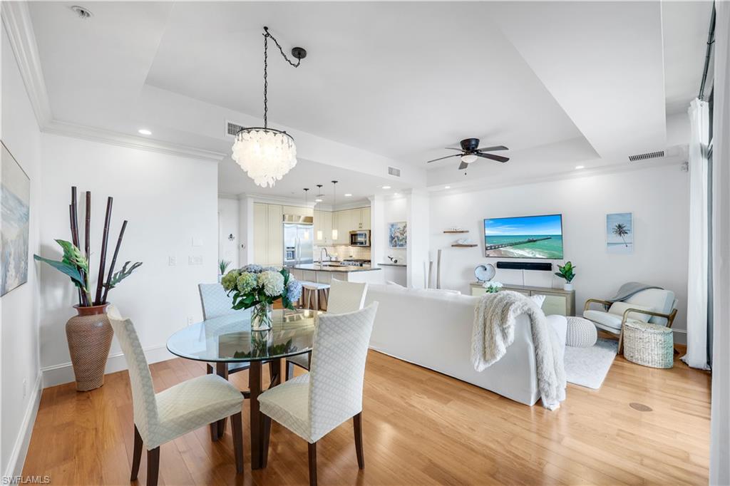 9123 Strada Place, Unit 7309 Naples, FL 34108 - Photo 5 of 48 Dining space featuring ceiling fan, light wood-type flooring, recessed lighting, a tray ceiling, and a chandelier