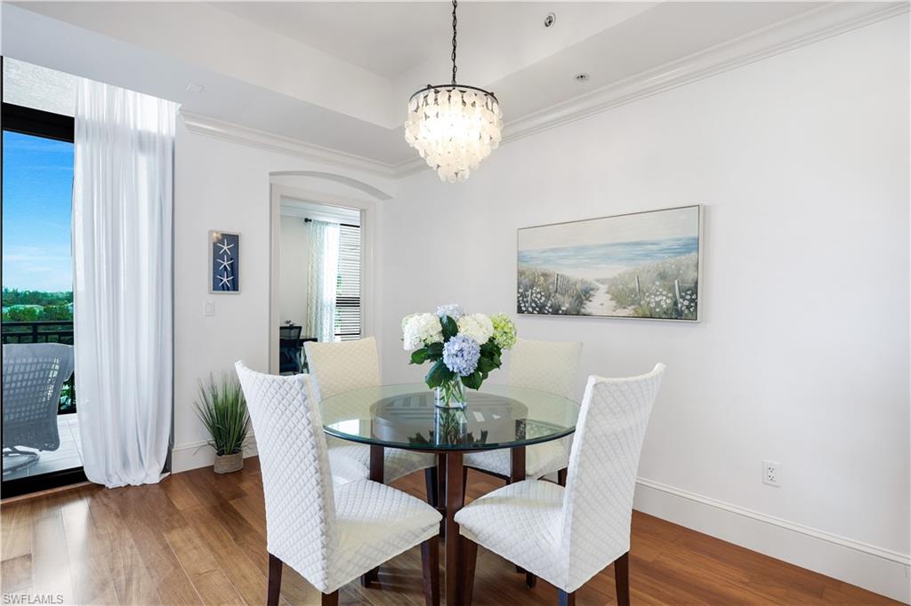 9123 Strada Place, Unit 7309 Naples, FL 34108 - Photo 7 of 48 Dining room featuring crown molding, wood finished floors, a chandelier, and a tray ceiling