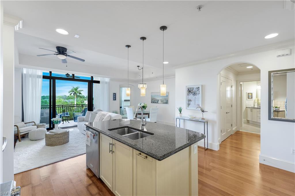 9123 Strada Place, Unit 7309 Naples, FL 34108 - Photo 48 of 48 Kitchen with open floor plan, dark stone countertops, New hanging light fixtures, light wood finished floors, and arched walkways